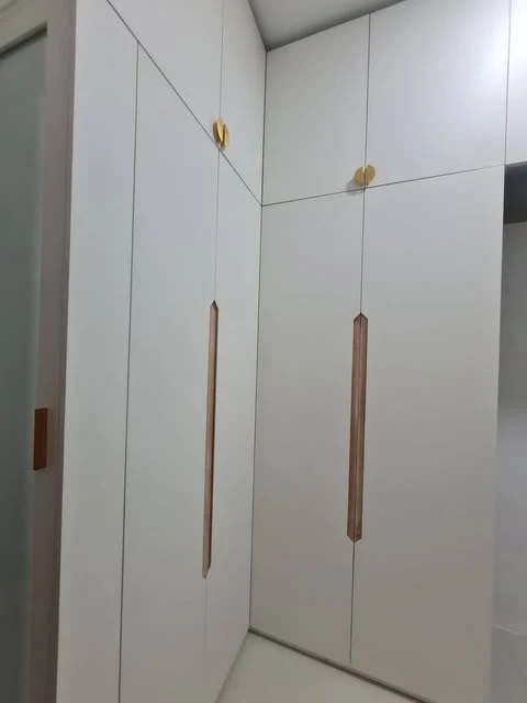 Wardrobe sudut berwarna terang dengan kabinet atas dan pegangan vertikal