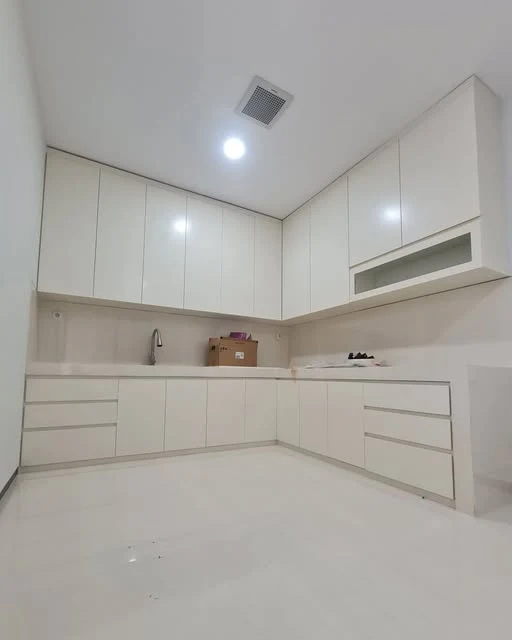 Kitchen set putih berbentuk L dengan deretan kabinet atas dan bawah